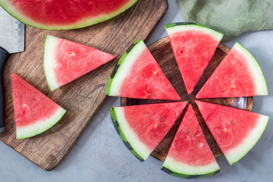 Slices of fresh seedless watermelon cut into triangle shape laying on wooden plate, flat lay, horizontal
