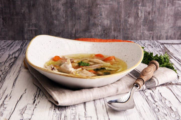 Bone broth made from chicken with carrots, onions various fresh vegetables in a pot - colorful fresh clear spring soup. Rural kitchen scenery bouillon or stock