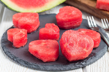 Slices of fresh seedless watermelon cut into heart shape on slate board, horizontal