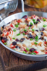 Baked casserole with black beans, pinto beans, kidney beans, rice, cheese and paprika, in a metal baking dish, vertical, closeup