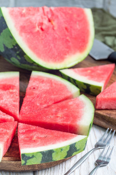 Slices of fresh seedless watermelon cut into triangle shape on wooden plate, vertical