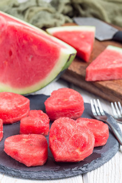 Slices of fresh seedless watermelon cut into heart shape on slate board, vertical