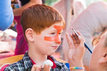 Child boy face painting, making tiger eyes process