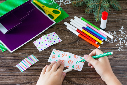 A child draws a greeting card details with Christmas presents. Made by own hands. Children's art project, craft for children. Craft for kids.