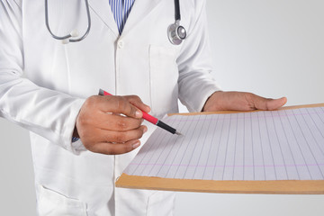 Male doctor in white uniform writing on clipboard paper