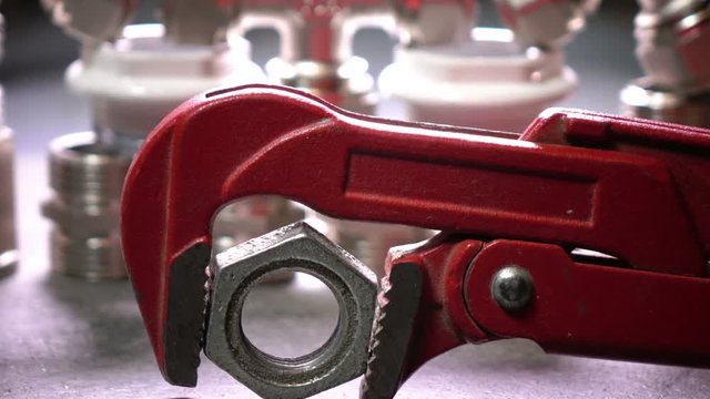 Red metalwork adjustable spanner for sanitary works against the background of Water shutoff and connecting shutoff valves for water supply