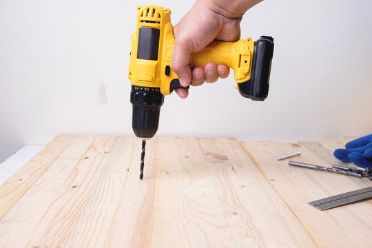 Craftsman working with power drill on wooden plank