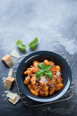 Potato gnocchi with meat sauce served in a plate on a grey stone background. Elevated view with space