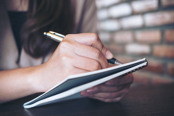 Closeup image of a business woman writing and taking note on notebook in office