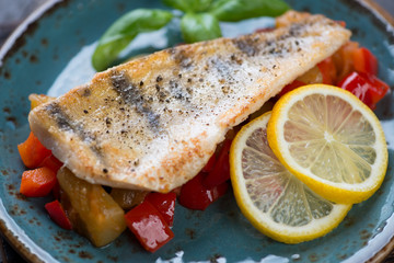 Close-up of roasted fillet of sudak fish served on sauteed vegetables, selective focus