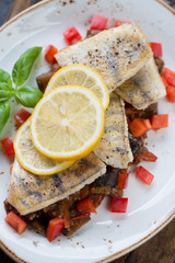 Close-up of roasted sudak fillet slices on sauteed vegetables, vertical shot