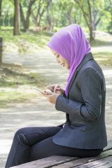 Young muslim woman smiling and holding the phone