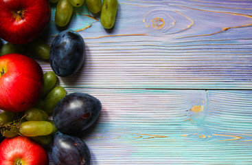 Apples, plums and grapes on a soft blue background