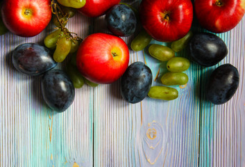 Apples, plums and grapes on a soft blue background