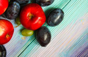 Apples, plums and grapes on a soft blue background