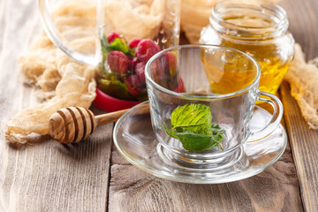 Glass cup for hot tea with raspberries, mint and honey