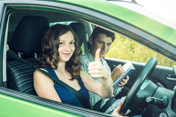 Instructor and Female student driving showing thumb up. Woman passed the exam in driving school.