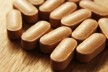 Medical pills on a wooden table.This image is a close up macro shot and has selective focusing.