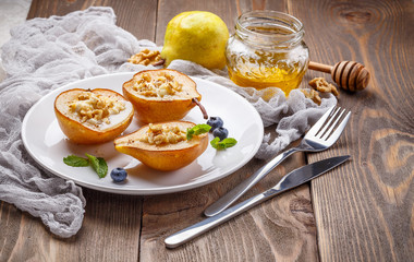 Pears baked with Ricotta cheese, nuts, honey and cinnamon on rustic wooden background