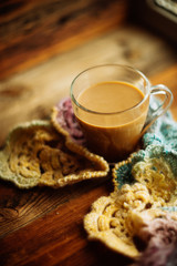 Cup of coffee wrapped in scarf on books background