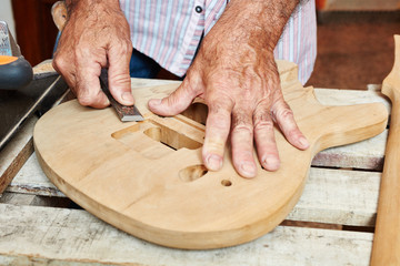 Gitarrenbauer bearbeitet Korpus der Gitarre