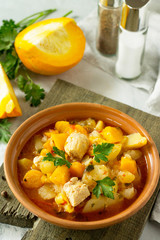 Turkey stew with pumpkin, vegetables and spices in a bowl on a stone background.