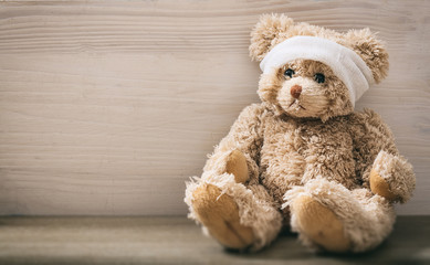 Teddy bear with bandage on a wooden floor