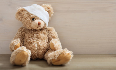 Teddy bear with bandage on a wooden floor