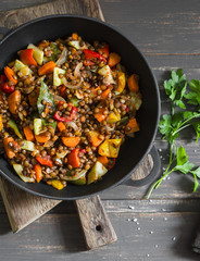 Lentils and seasonal garden vegetables braised in the pan on wooden background, top view. Autumn vegetarian healthy lunch