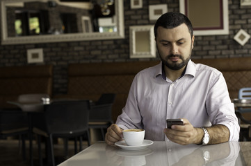 Handsome man using phone in cafe