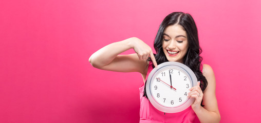 Young woman holding a clock showing nearly 12