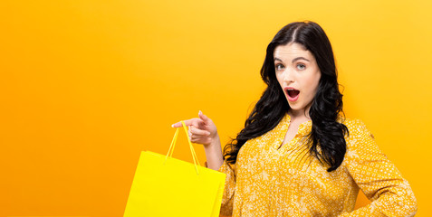 Young woman holding a shopping bag on a solid background