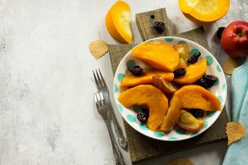 Pumpkin baked with apples, prunes and spices in a bowl on a stone background. Flat flay, top view with copy space.