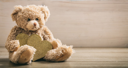 Teddy bear holdimg hearts on a wooden floor