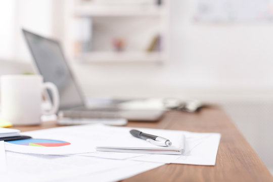 Side view of office desk with pen on the notebook, laptop and other items