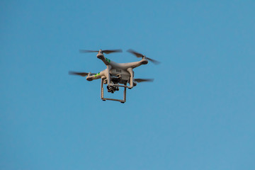 Quadcopter drone with the camera hovering in blue sky