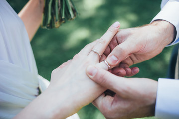 Groom wearing wedding ring on finger of bride