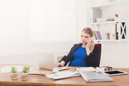Pregnant business lady at work talking on phone