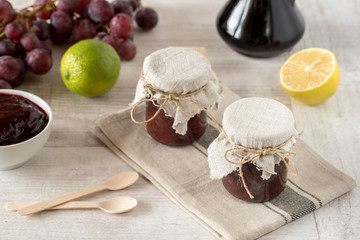 Homemade jam in small glass jars. Fresh grapes in background.
