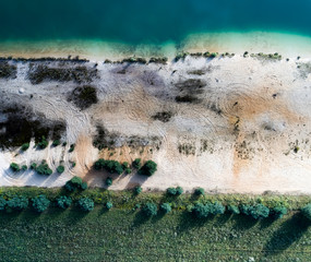 Abstract photo with the drone, blue streaks of water, white strips of sand, green strips of grass
