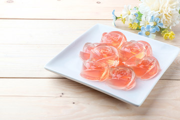 Jelly in rose shape in plate on wooden background
