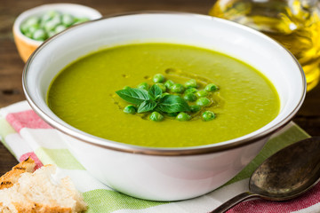 Green pea soup in bowl on wooden table