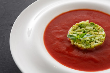 Cold tomato soup gazpacho with avocado close up