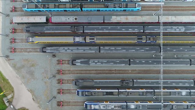 Aerial railway hub showing passenger trains on tracks next to each other top down view drone moving up slowly showing more and more railway tracks positioned horizontally above each other 4k quality