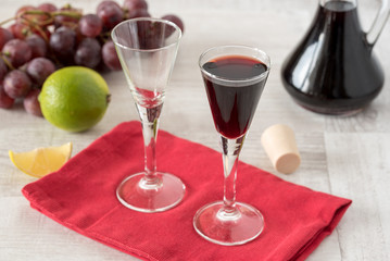 Homemade liqueur in glass and bottle with fresh grapes in background.