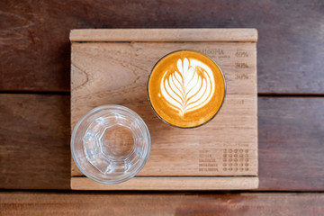 Cup of hot latte milk coffee with glass of plain water. Concept of modern cafe / coffee shop serving Australian style specialty coffee