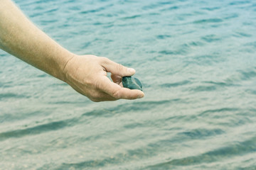 A man throws a stone in the sea