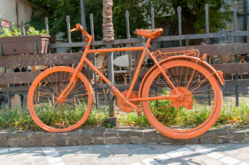 Fototapeta na wymiar Orange bicycle on the road side.