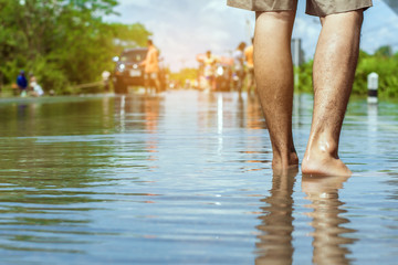 young man walks through the flood with his bare feet.