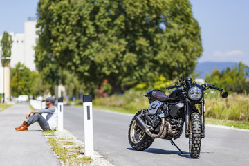 Motorcycle rider sitting near custom made scrambler style cafe racer
